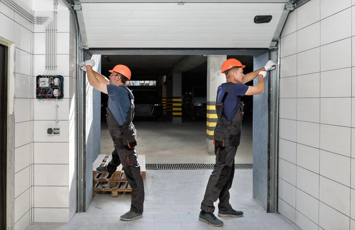 Technicians conduct final adjustments on a commercial garage door, ensuring proper operation and safety compliance.